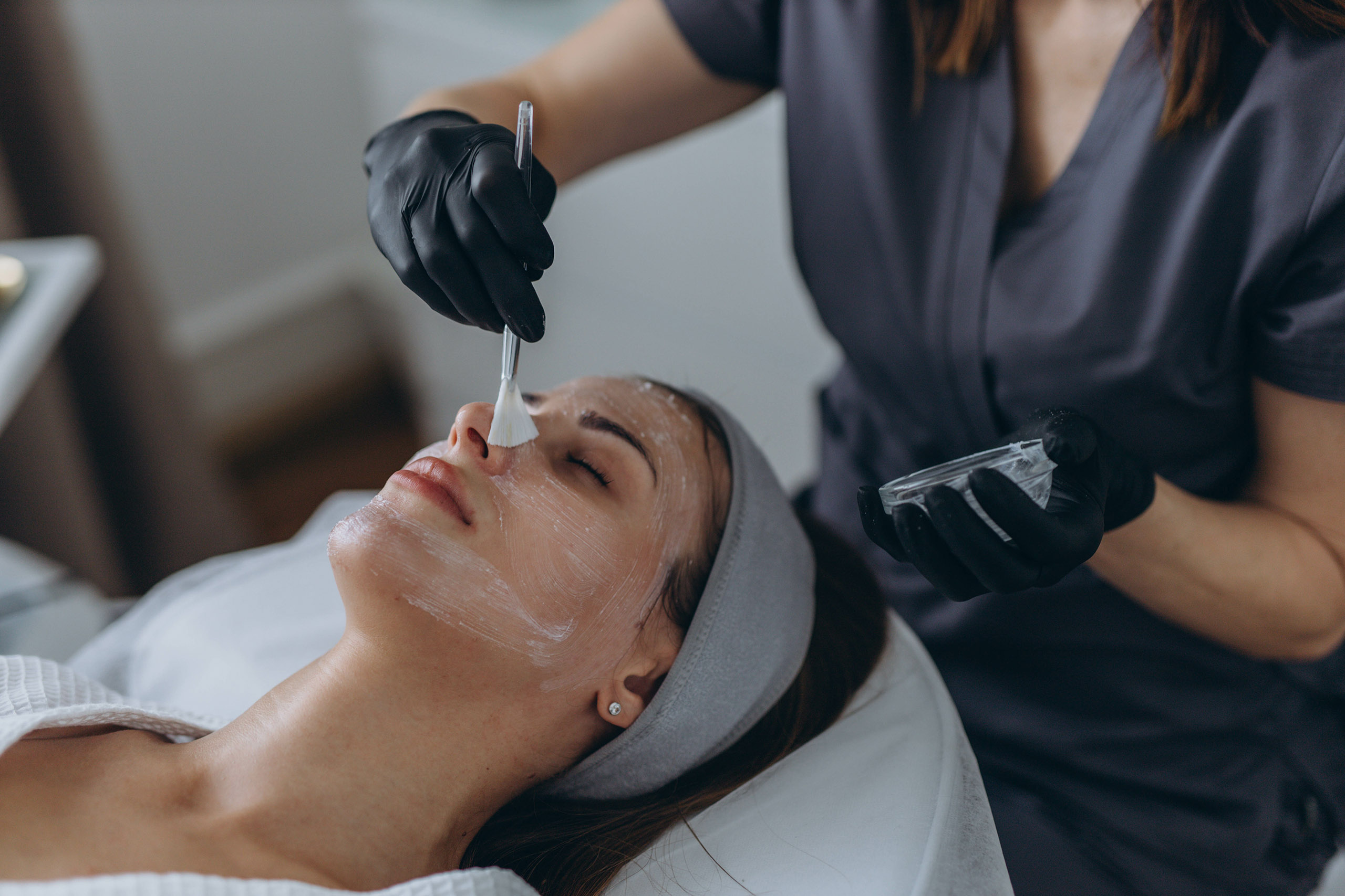 Cosmetologist performs a facial peeling procedure on a young woman. High quality photo