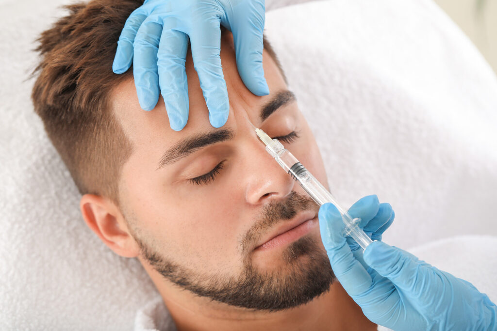 Handsome man receiving filler injection in clinic