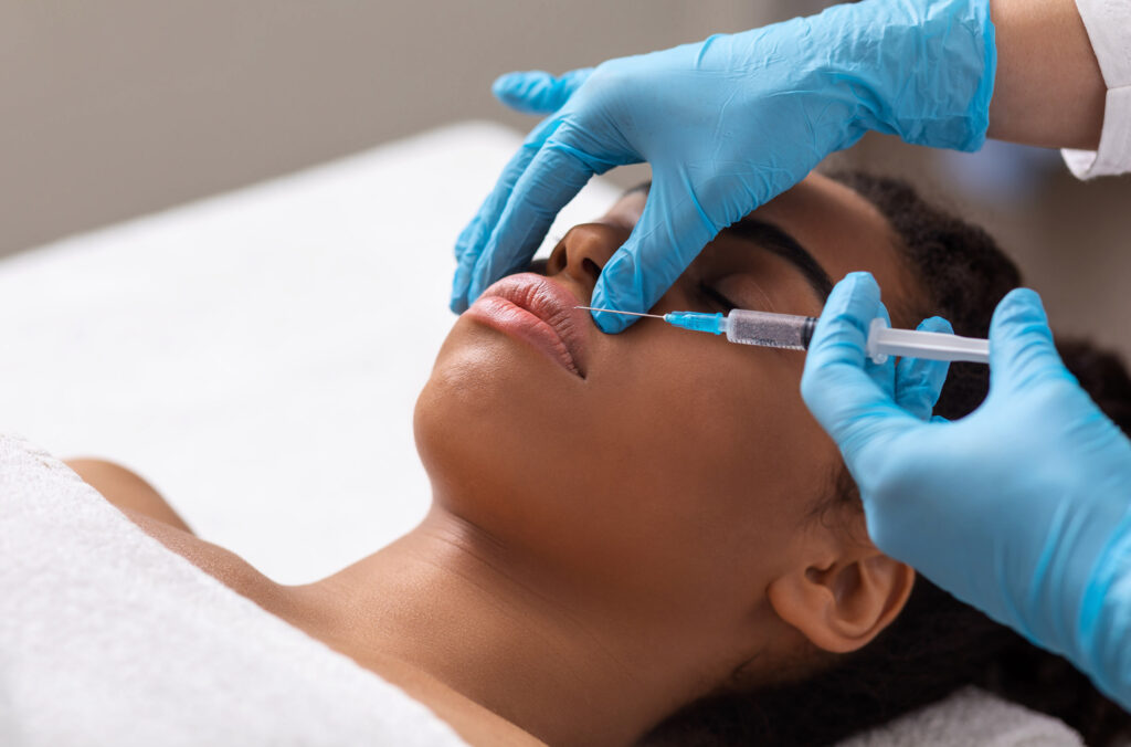 Black lady getting lip filling injection at modern beauty salon, closeup, copy space