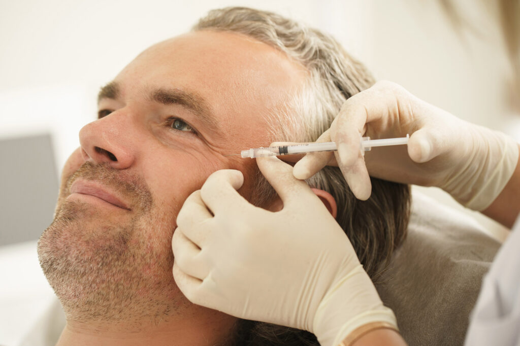 Middle aged male client during filler injections in aesthetic medical clinic