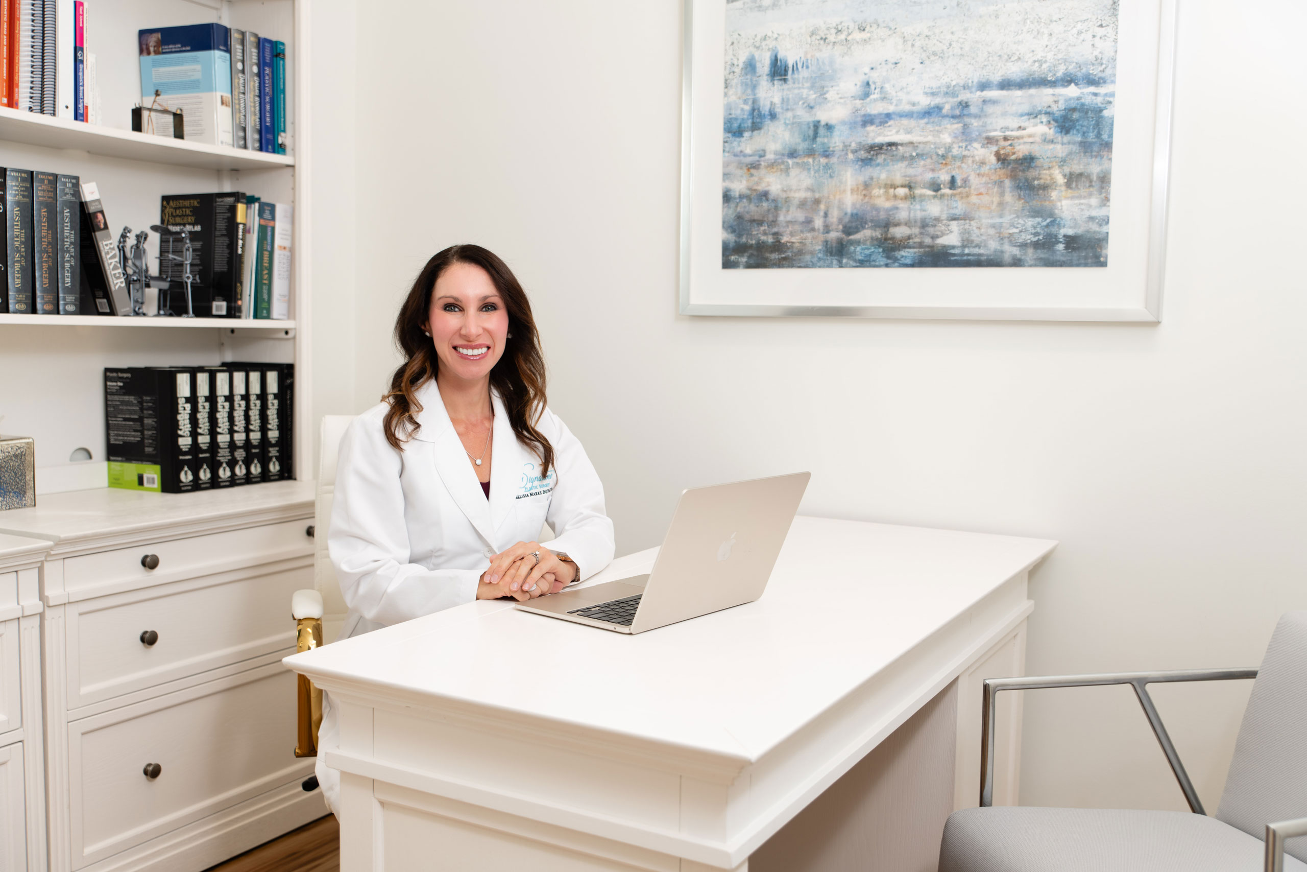 Dr. Melissa Marks sitting in her professional lab coat at her desk at her office