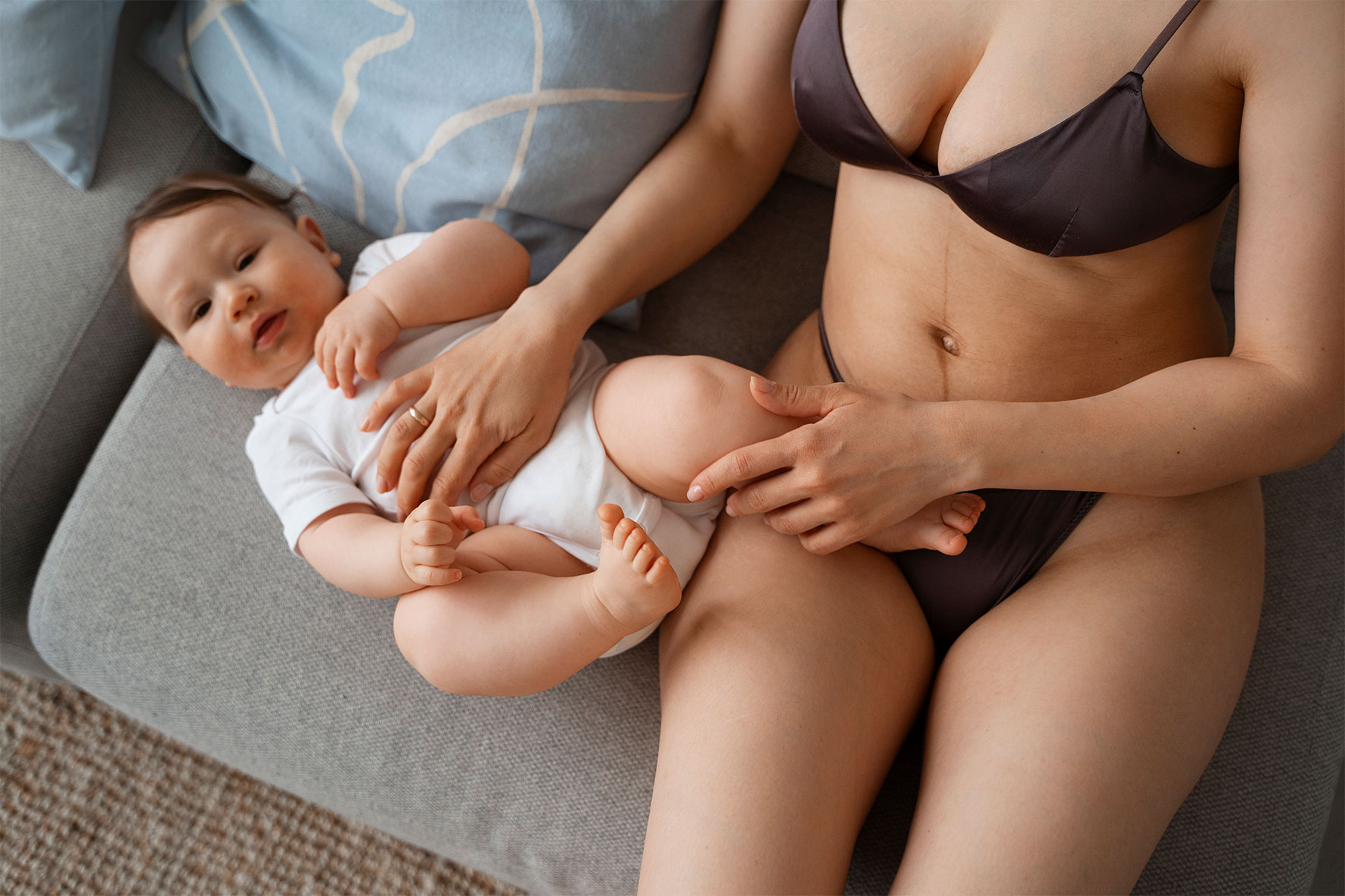 New mother sitting on the couch with her 5 month old baby