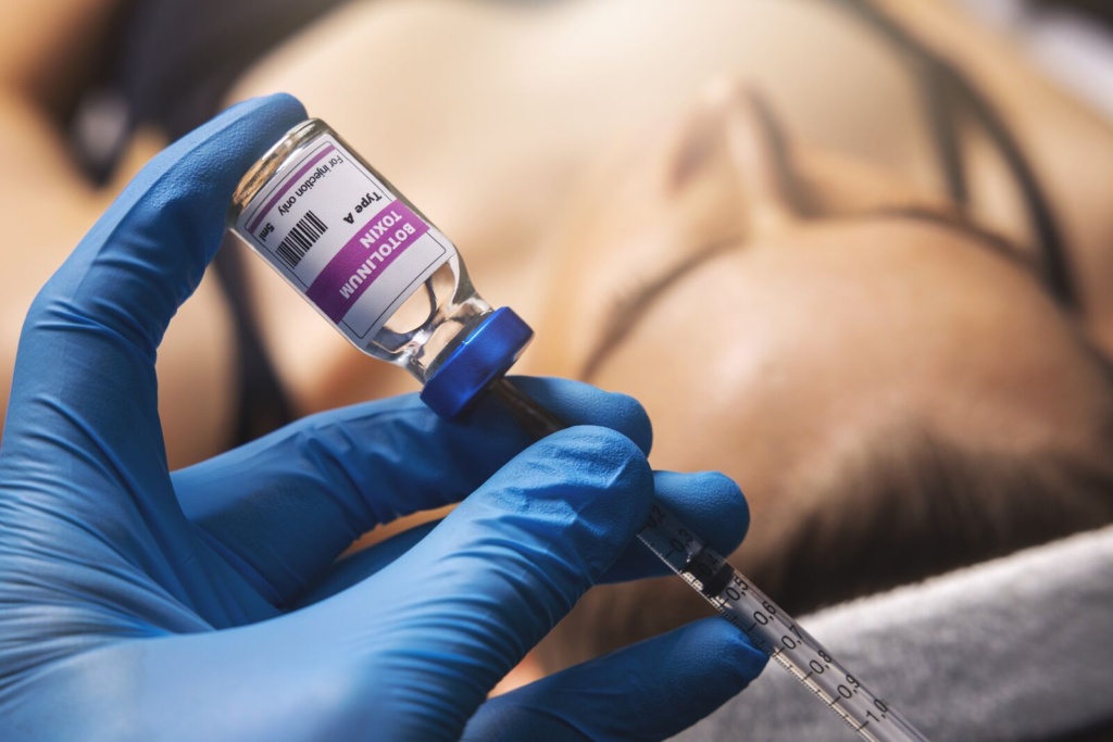 Provider drawing Botox from a vial before a facial treatment