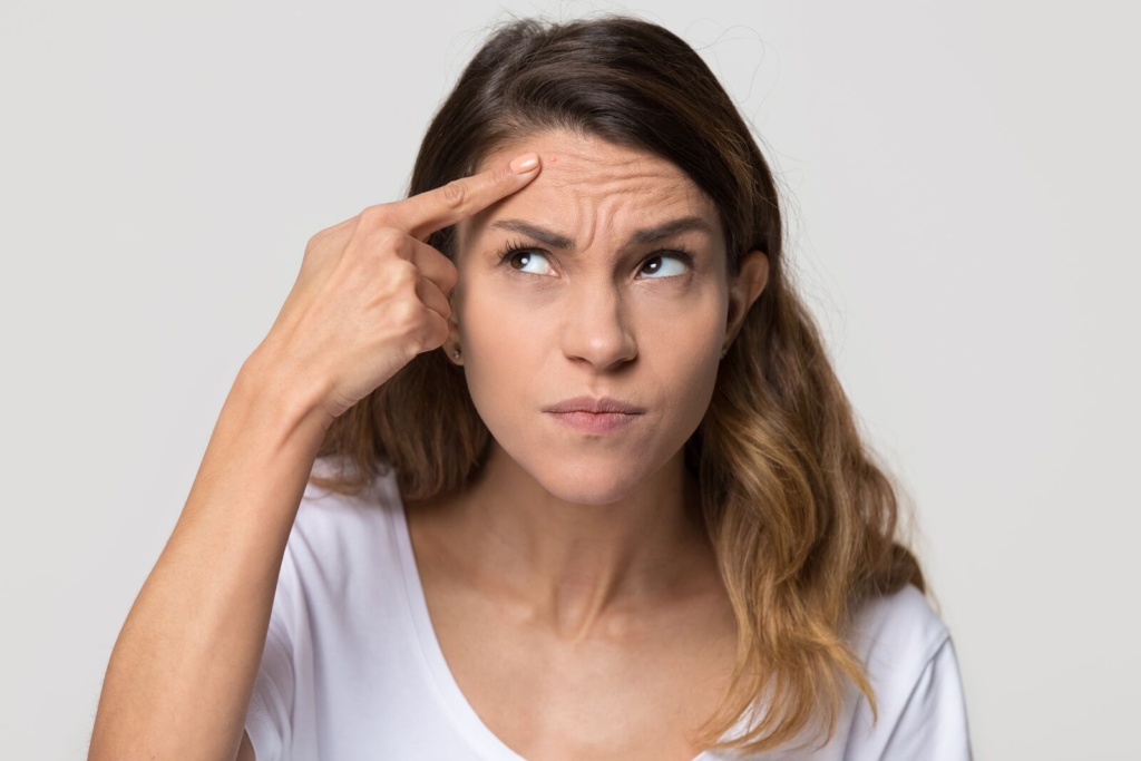 Woman pointing to the frown lines between her brows